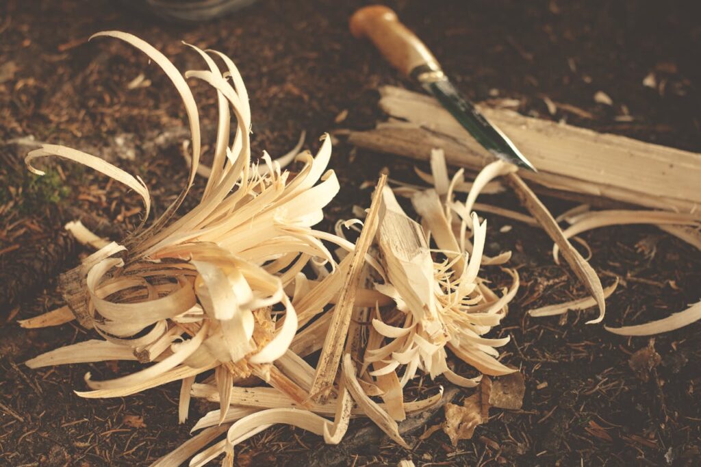 Mesa de trabajo Woodworking knife and wood shavings on ground, showcasing craftsmanship in a rustic outdoor environment.