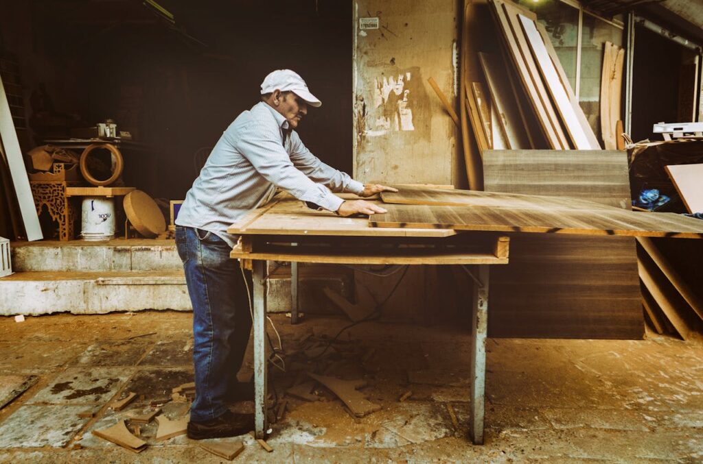 corte de piezas Carpenter focuses on woodworking project inside a busy workshop, surrounded by materials.